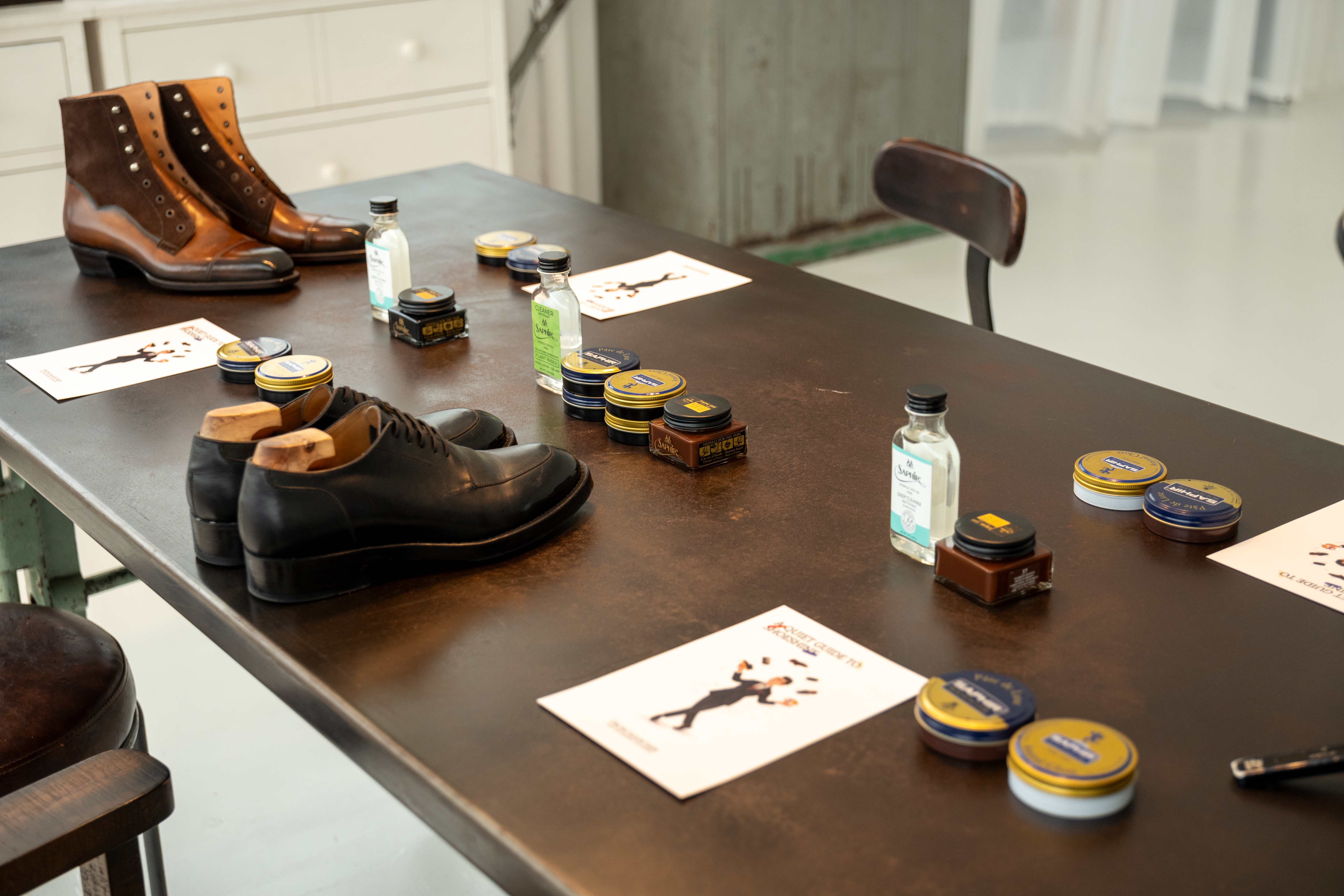 The Ritual table setup — cards placed at every seat alongside shoes and Saphir products